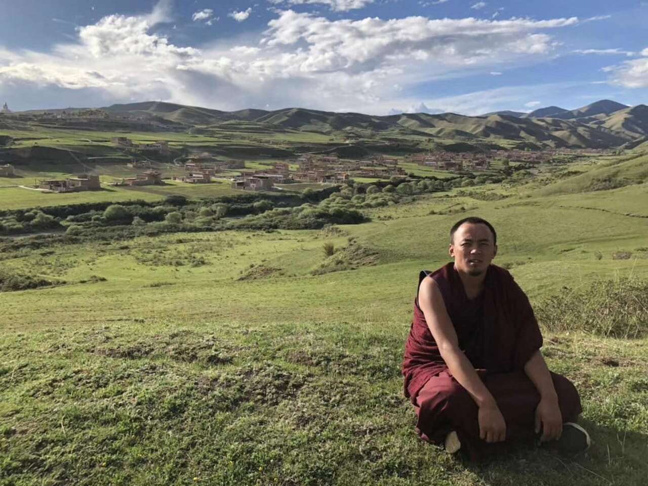 Rinchen Tsultrim sitting on the alpine meadow of a Tibetan village