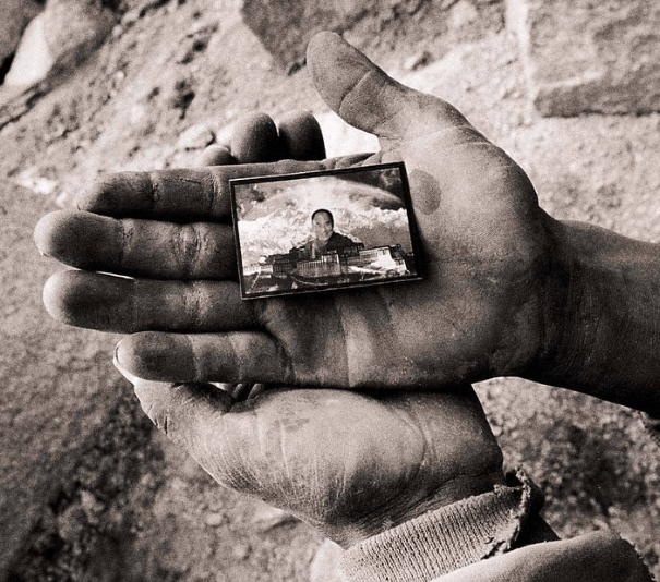 A miniature photo of His Holiness the Dalai Lama above the Potala Palace held with respect Image source: TibetMuseum/Pinterest